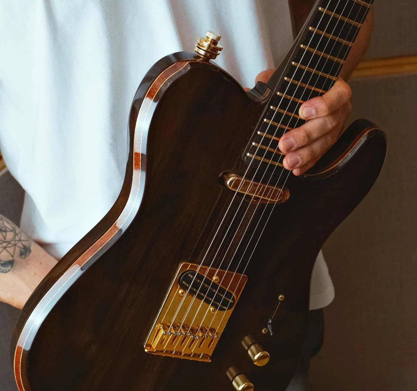 A musician holding a Kadence electric guitar with gold hardware