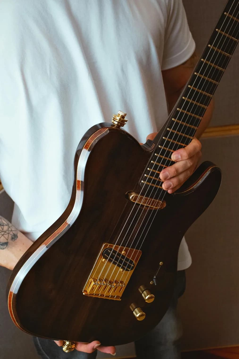 A musician holding a Kadence electric guitar with gold hardware